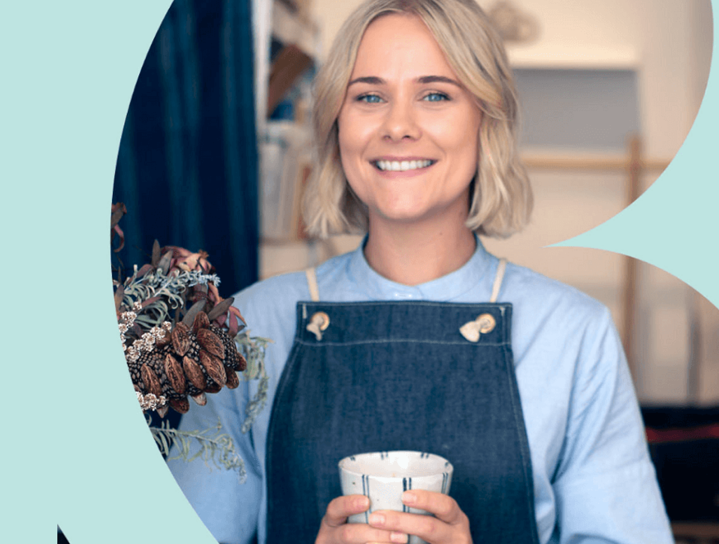 Smiling ClassBento teacher in a denim apron holding a cup of coffee.